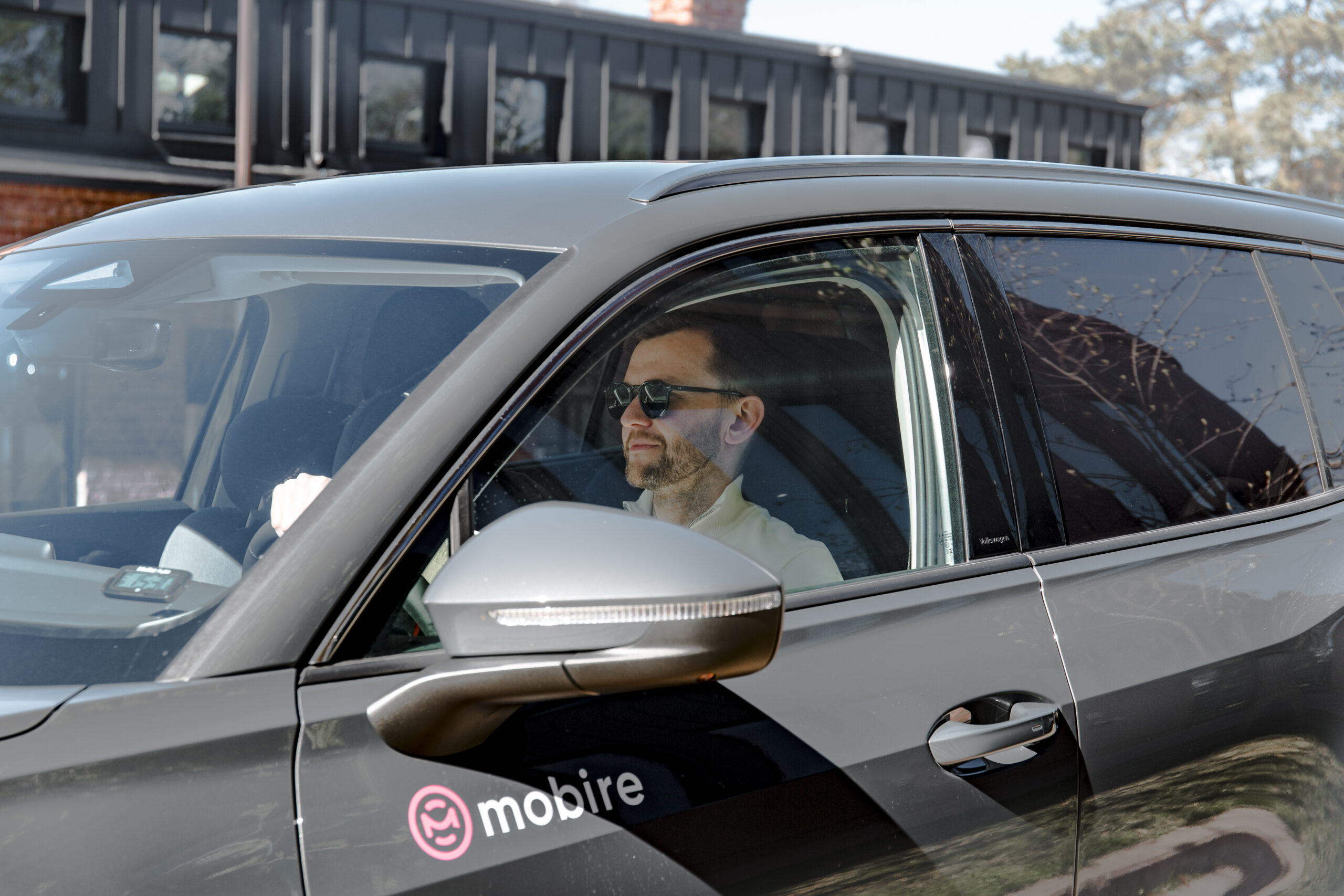Vyras vairuoja įmonės automobilį su Mobire logotipu – veiklos nuoma su paslaugomis verslui.