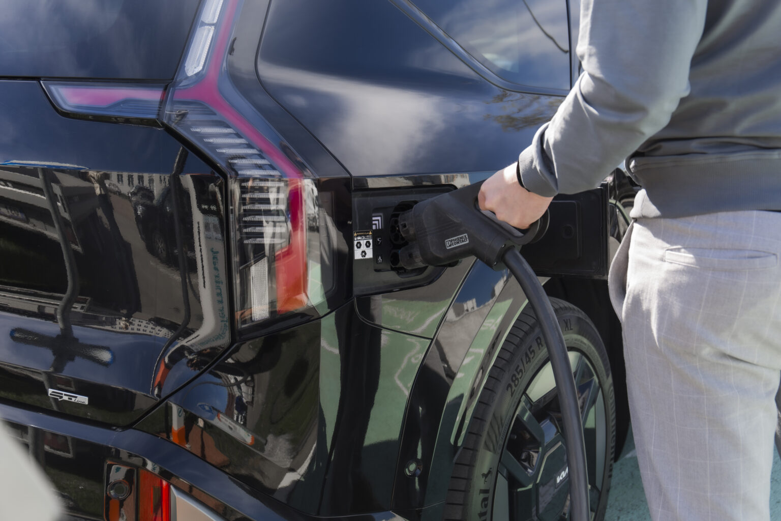 žmogus įkrauna elektrinį automobilį