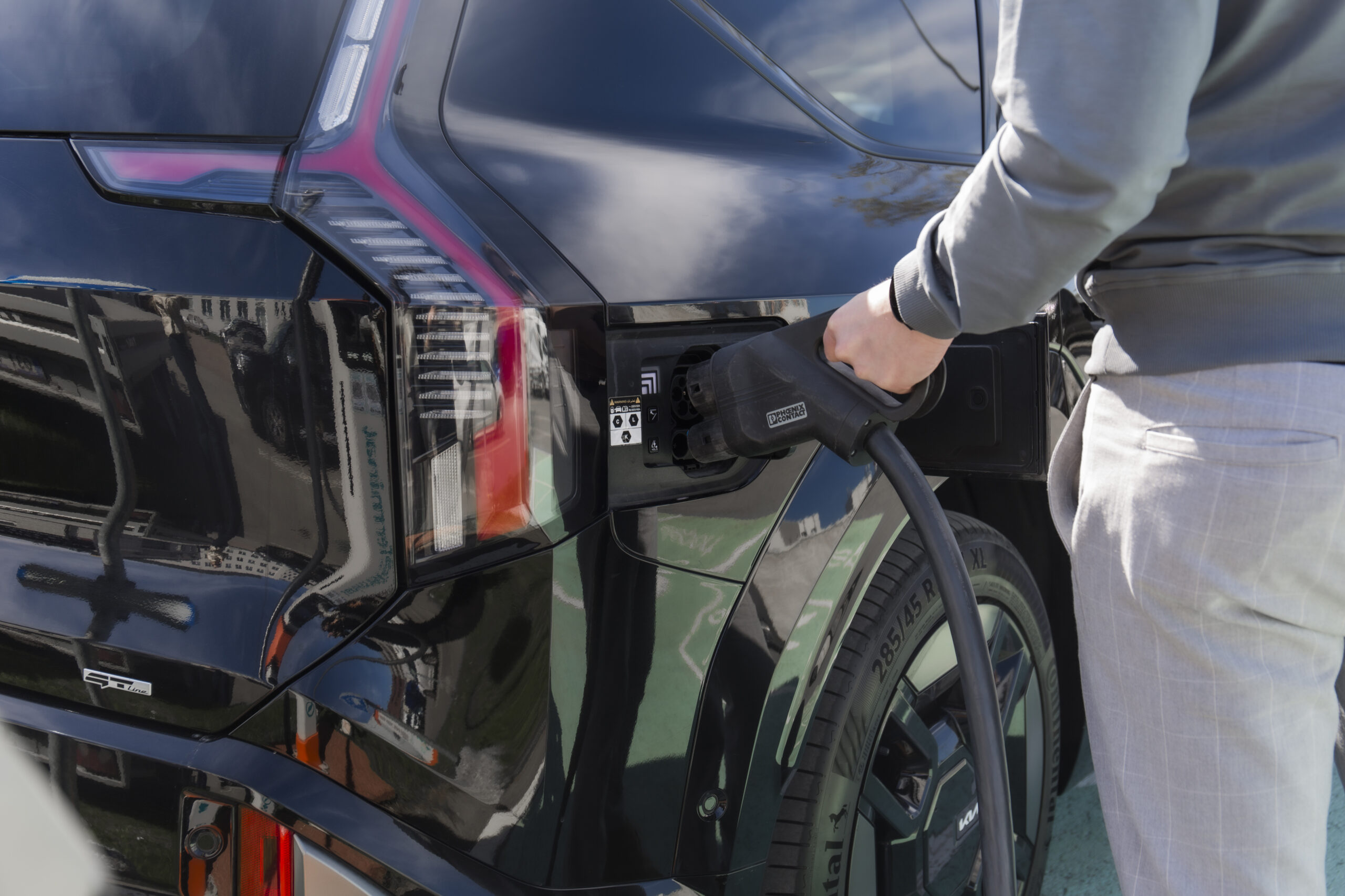žmogus įkrauna elektrinį automobilį
