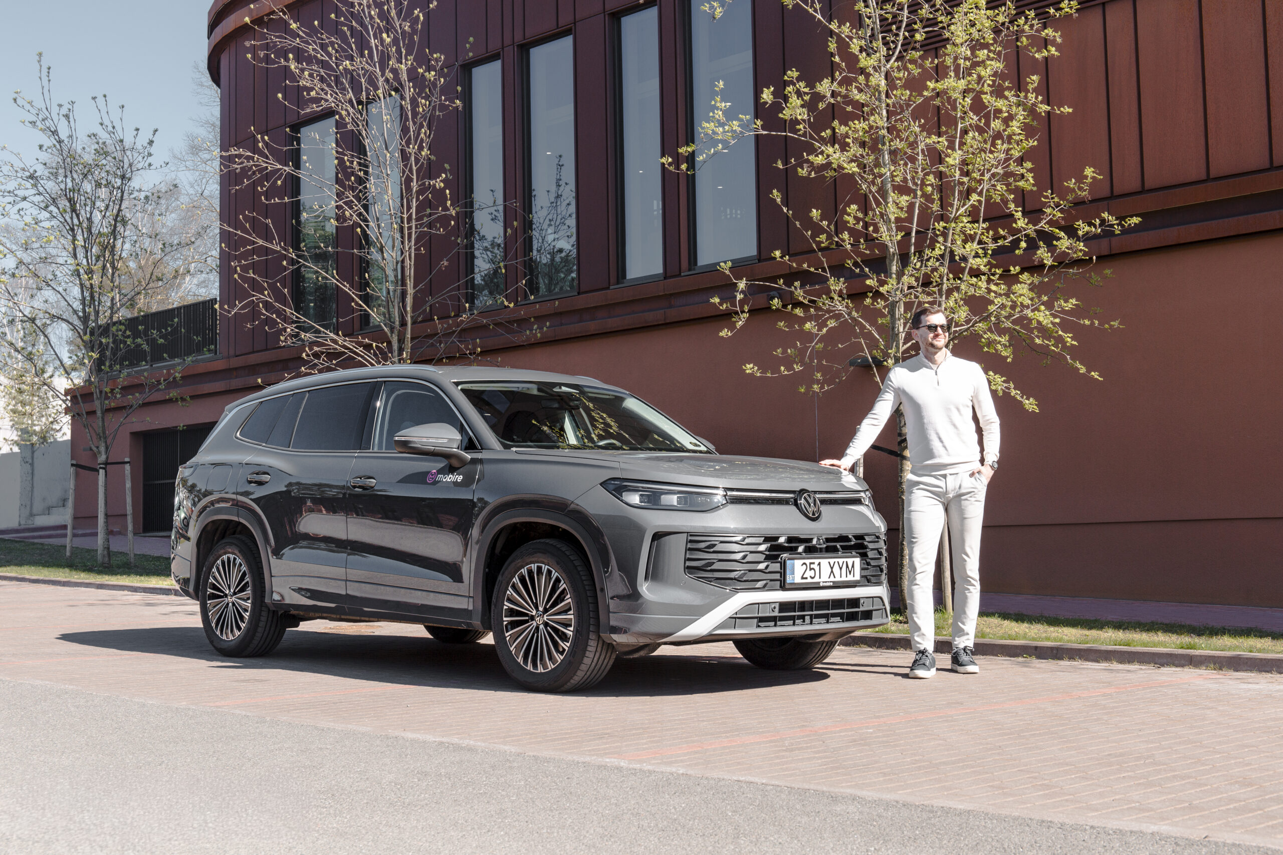 Мужчина стоит рядом с новым внедорожником Volkswagen Tayron автопарк компании