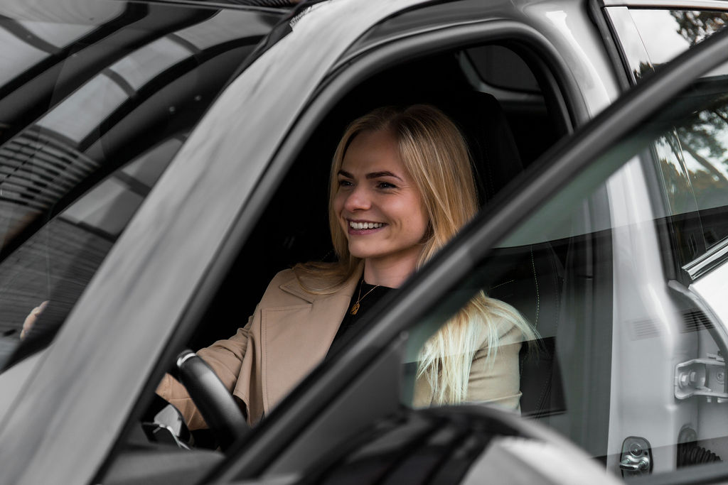 Ilgalaikė automobilių nuoma. Besišypsanti moteris automobilyje